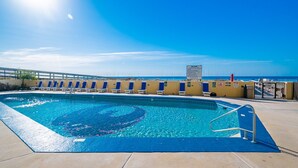 En swimmingpool med ett solskydd, en livräddarstation och fri sikt ut över havet.