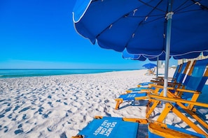 A beach with rows of blue and yellow beach chairs under blue umbrellas, facing the ocean. - Phoenix Iv 4122 1 Bedroom Condo (Orange Beach)