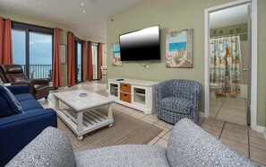 Una sala de estar con sofá, sillón, mesa de centro, televisor y vistas al balcón.