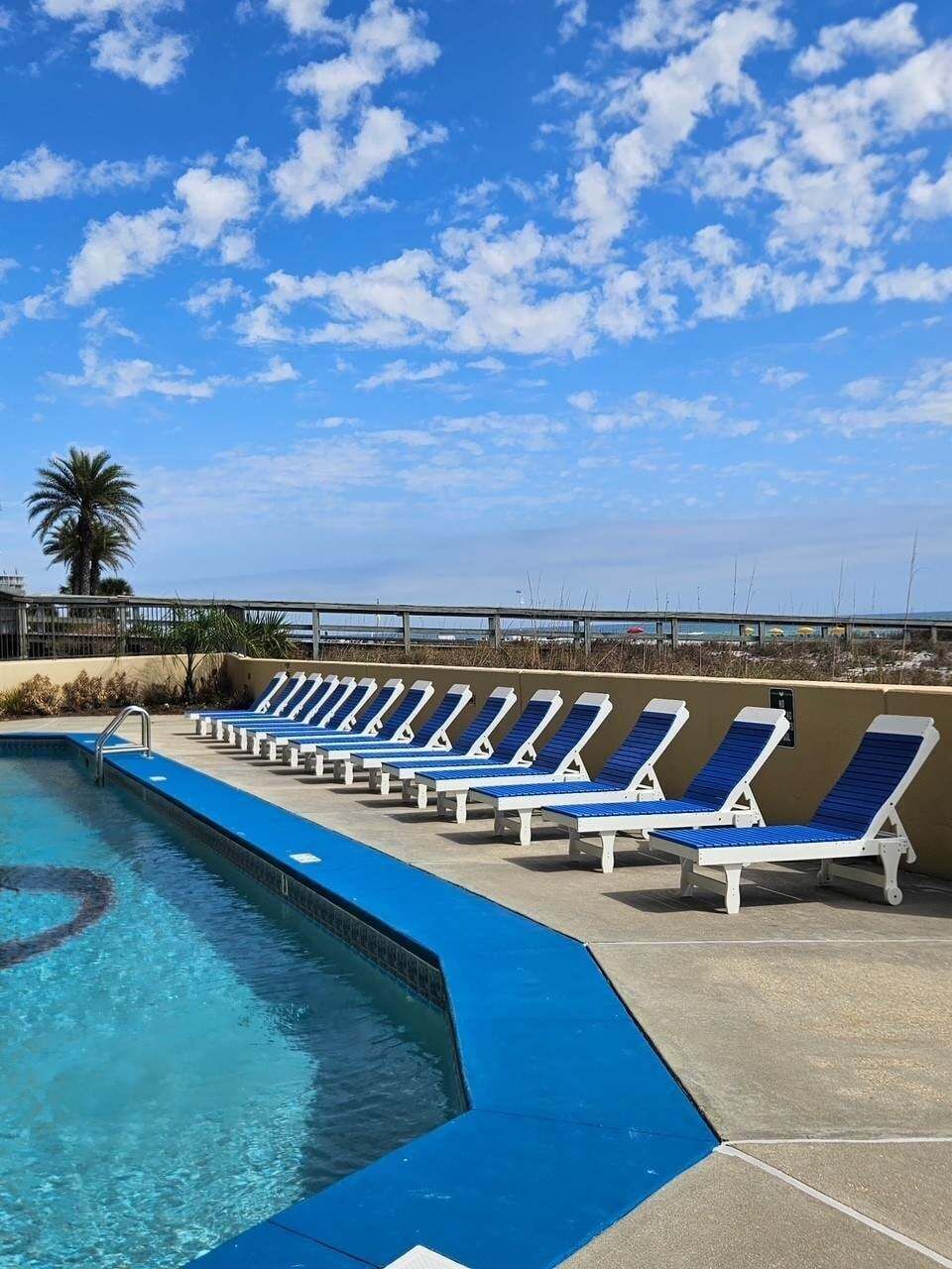 Ein Swimmingpool mit blauen und weißen Liegestühlen, die am Rand angeordnet sind.