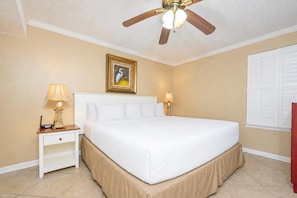 A hotel room with a bed, bedside lamps, a ceiling fan, a framed picture on the wall, and a window with blinds. - Phoenix Iv 4102 1 Bedroom Condo (Orange Beach)