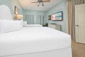 A hotel room with a large bed, a ceiling fan, a television, and a view of the ocean. - Phoenix Ix 1202 2 Bedroom Condo (Orange Beach)