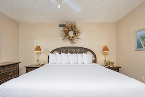 A hotel room with a large bed, two bedside tables with lamps, a decorative wreath on the wall, and a framed picture. - Phoenix Iv 4104 2 Bedroom Condo (Orange Beach)