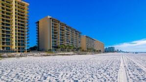 A beachfront hotel with multiple high-rise buildings, sandy beach, and clear blue sky. - Phoenix Iv 4062 1 Bedroom Condo (Orange Beach)