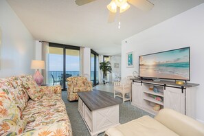 A living room with a sofa, a coffee table, a TV, and a balcony with a view of the sea. - Phoenix Iv 4062 1 Bedroom Condo (Orange Beach)