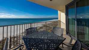 A balcony with a table and chairs, overlooking a beach and ocean. - Phoenix Iv 4062 1 Bedroom Condo (Orange Beach)
