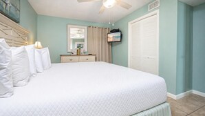 A bedroom with a large bed, a dresser, a television, and a ceiling fan. - Phoenix Iv 4022 1 Bedroom Condo (Orange Beach)