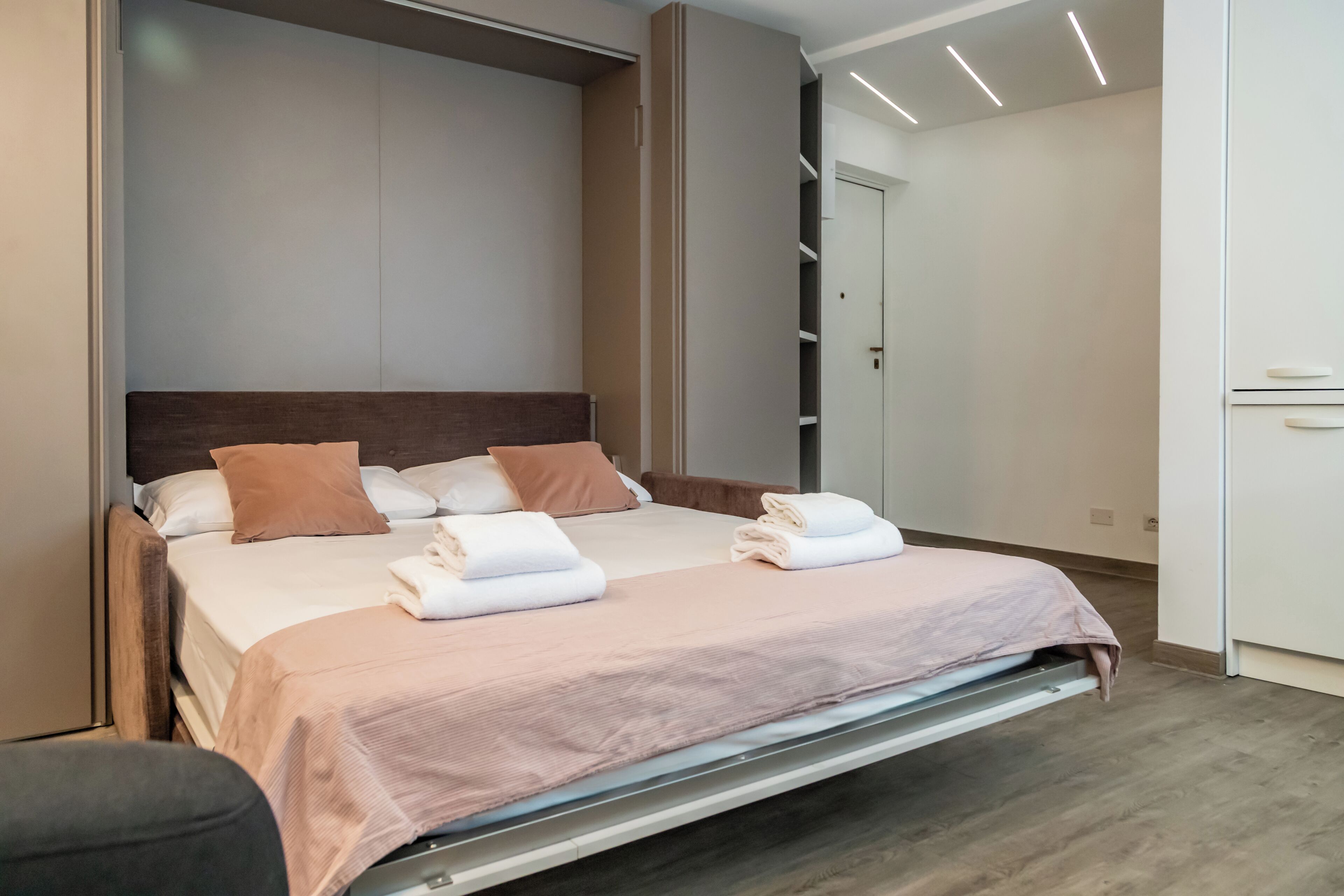 A modern bedroom with a bed, pillows, and a neatly made bedspread.