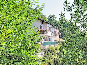 Ein mehrgeschossiges Gebäude mit Balkonen, umgeben von üppiger Vegetation.