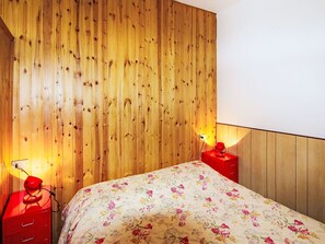 Ein Schlafzimmer mit einem hölzernen Kopfteil, einer blumigen Tagesdecke und zwei Nachttischen mit Lampen.