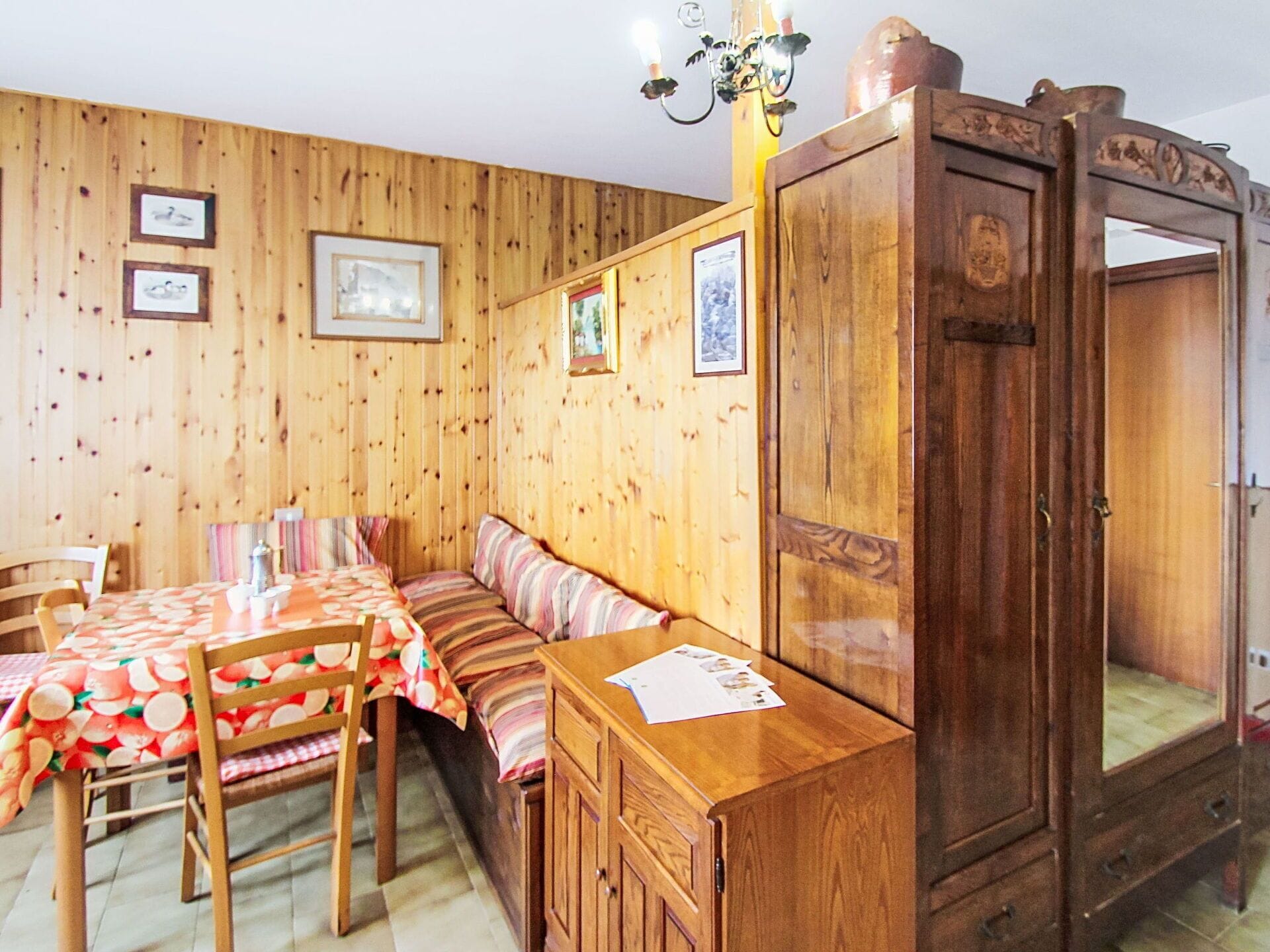Una habitación con paneles de madera, una mesa de comedor, sillas, un banco y un armario.