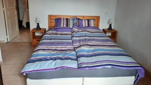 A bedroom with a bed, two bedside tables, and a door leading to another room. - Breathtaking view of Lake Serre-Ponçon (Chorges)