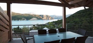 Eine Terrasse mit Tisch und Stühlen mit Blick auf einen See und Berge.