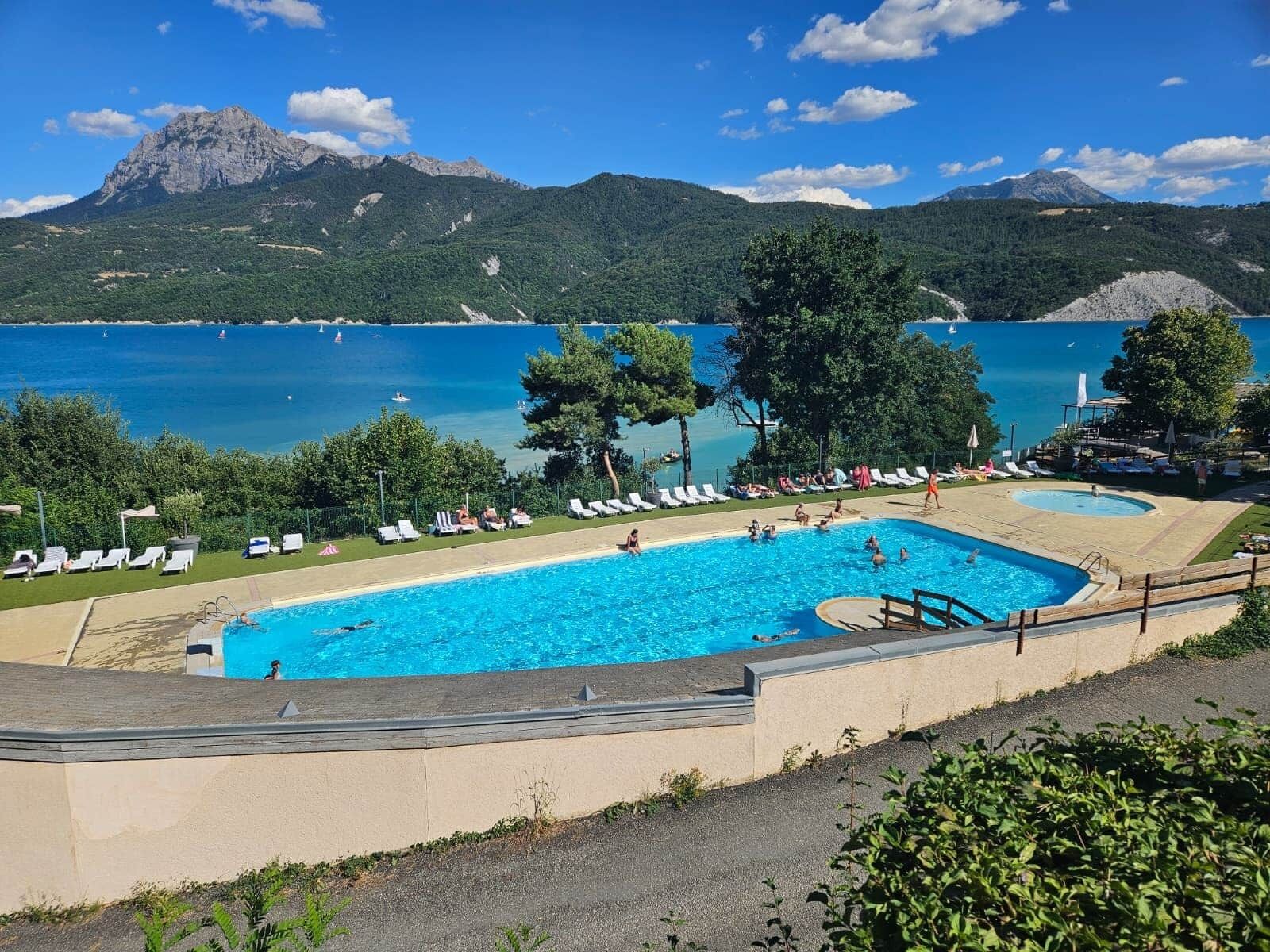 Une piscine dotée de chaises longues et offrant une vue sur un lac et des montagnes.