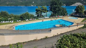 A swimming pool with lounge chairs and a view of a lake and mountains. - Breathtaking view of Lake Serre-Ponçon (Chorges)