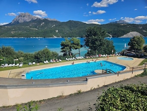 Ein Schwimmbecken mit Liegestühlen und Blick auf einen See und Berge.