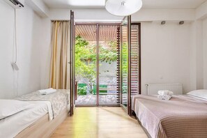 A modern bedroom with two beds, a large sliding glass door to a balcony, and a ceiling light. - Perfect 4-bedroom apartment with AC in serene T'bilisi (T'bilisi)