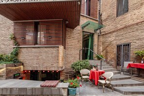 Un espace extérieur aménagé avec une table, une nappe rouge, un mur en briques et une pergola en bois.