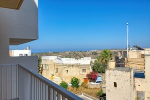 A balcony overlooking a coastal town with stone buildings and a clear sky. - Xag ra Apartment With Sea Views Balcony Gozo (Xaghra)