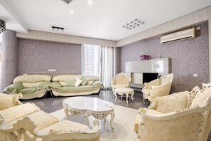 A spacious living room with a sofa set, armchairs, a coffee table, and a fireplace. - Beautiful 3-bedroom apartment with AC in vibrant Tbilisi (tbilisi)