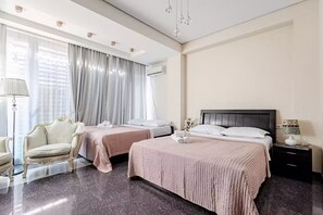 A hotel room with two beds, a sitting area with a chair, a nightstand with a lamp, and a large window with curtains. - Beautiful 3-bedroom apartment with AC in vibrant Tbilisi (tbilisi)