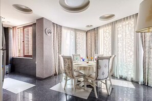 A dining area with a round table, chairs, and a clock on the wall. - Beautiful 3-bedroom apartment with AC in vibrant Tbilisi (tbilisi)
