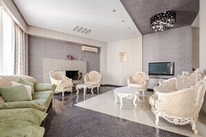 Ein geräumiges Wohnzimmer mit Kamin, Flachbildfernseher und aufwendigen weißen Möbeln.