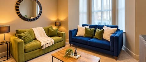 A living room with two sofas, a coffee table, a mirror, and a lamp.