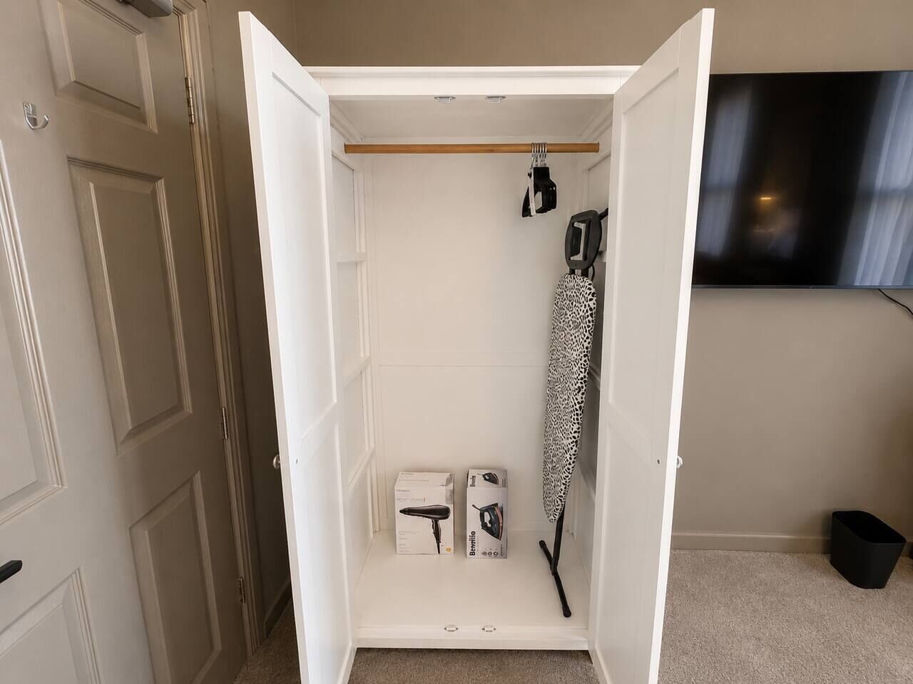 Un vestidor con barra para colgar, una caja de almacenamiento y un objeto estampado.