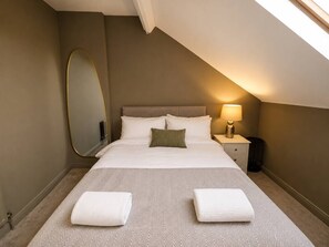 A bedroom with a bed, bedside tables, a lamp, a mirror, and a window.