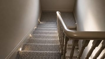 A staircase with a patterned carpet leading to a landing with a window.