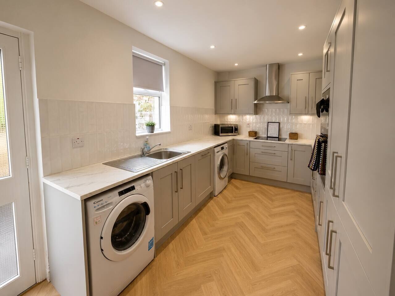A compact kitchen with a washing machine, microwave, and built-in oven.