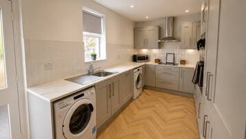 A compact kitchen with a washing machine, microwave, and built-in oven.