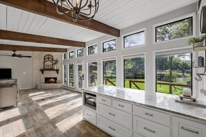 A spacious kitchen with a stone fireplace, large windows, and a view of the outdoors. - Waterfront 3 bed, 2 bath lake-house on Cedar Creek (Mabank)