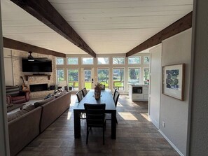 A spacious dining area with a long table and chairs, a fireplace, and a stone wall. - Waterfront 3 bed, 2 bath lake-house on Cedar Creek (Mabank)