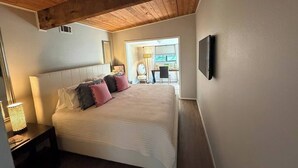 Ein Schlafzimmer mit Bett, Nachttischen, einer Lampe, einem Fernseher und einem Fenster.