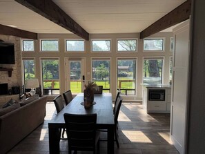 A dining area with a table and chairs, a kitchen with a microwave, and large windows offering a view of the outdoors. - Waterfront 3 bed, 2 bath lake-house on Cedar Creek (Mabank)