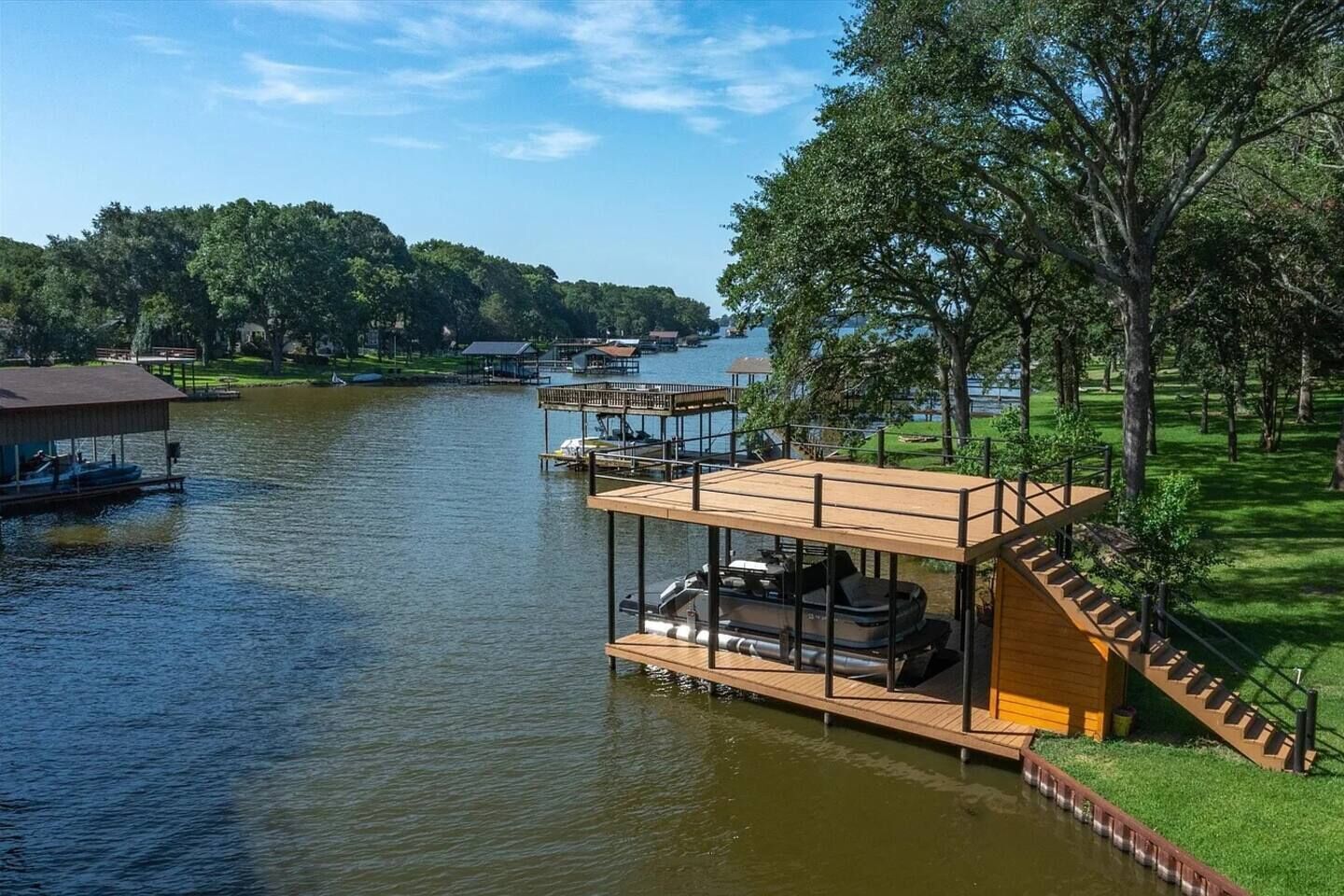 A waterfront property with a wooden deck, a boat, and a dock.