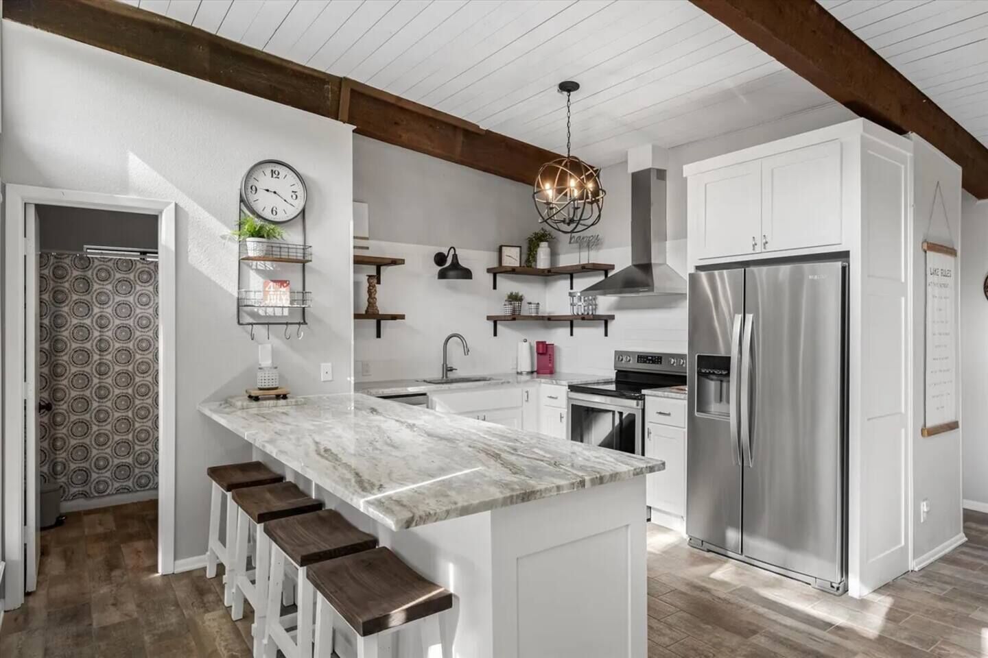 A modern kitchen with a central island, stainless steel appliances, and wooden beams on the ceiling.