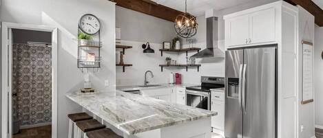 A modern kitchen with a central island, stainless steel appliances, and wooden beams on the ceiling.