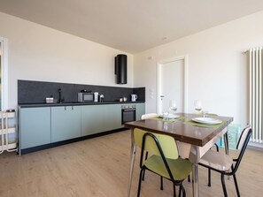 Une cuisine moderne avec un coin repas, équipée d’un four à micro-ondes, d’une bouilloire et d’un four.