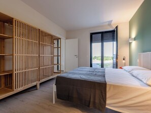 Ein Schlafzimmer mit einem Bett, einem Kleiderschrank und einem großen Fenster.