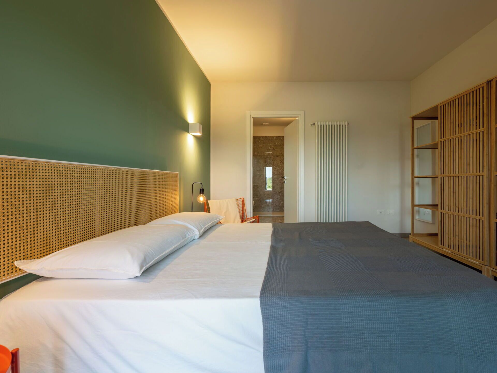 Une chambre d’hôtel avec un grand lit, une tête de lit en bois, une table de chevet avec une lampe et une armoire avec une porte coulissante.