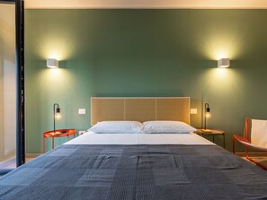 Ein Hotelzimmer mit einem großen Bett, zwei Nachttischen, einem Sessel und einer Wandleuchte.
