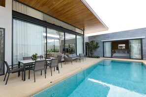 A modern outdoor pool area with a dining set and lounge chairs. - Botanica Pru Jampa New 3BR Pool Villa (ตำบล เทพกระษัตรี)