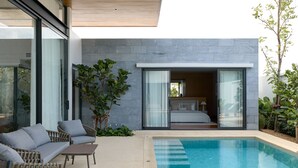 A modern outdoor pool area with a glass-enclosed bedroom visible through the sliding doors. - Botanica Pru Jampa New 3BR Pool Villa (ตำบล เทพกระษัตรี)