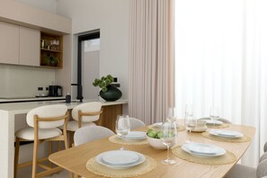 A modern dining area with a wooden table set for four, surrounded by chairs. - Botanica Pru Jampa New 3BR Pool Villa (ตำบล เทพกระษัตรี)