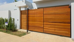 A modern house with a large wooden garage door and a small garden. - Botanica Pru Jampa New 3BR Pool Villa (ตำบล เทพกระษัตรี)