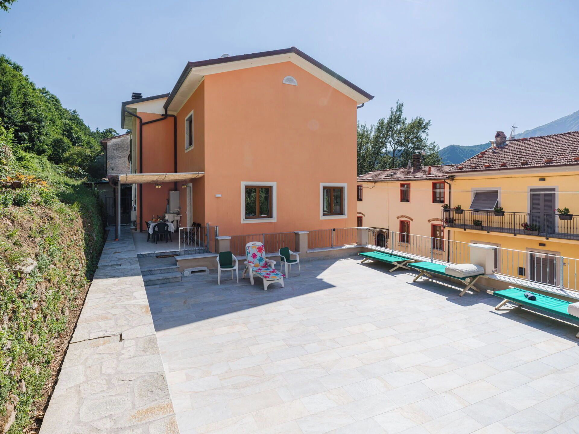 Ein Gebäude mit einer Terrassenanlage, inklusive Sitzgelegenheiten und Liegestühlen.