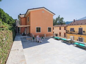 A building with a patio area featuring outdoor seating and sun loungers. - Beautiful apartment for 4 guests with WIFI, TV, patio and pets allowed (Seravezza)